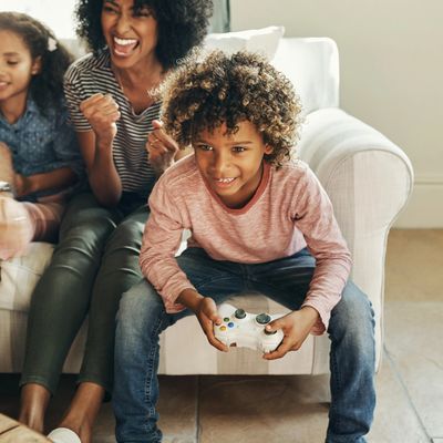 A boy playing video games with family cheering behind him.