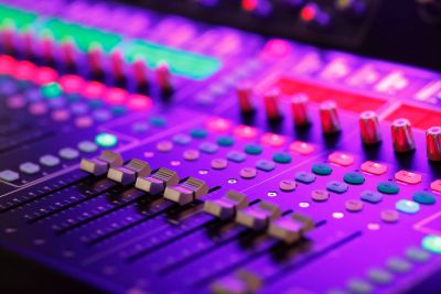 Close-up of a colorful sound mixing console with sliders and knobs.