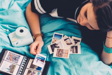 Person reminiscing over printed photos and a photo album.