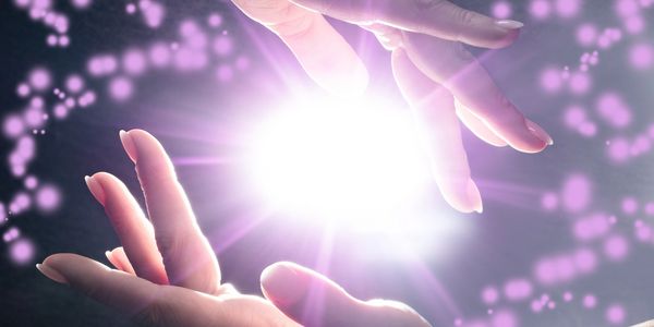 Hands creating a glowing orb with purple sparkles.