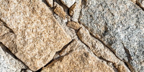 Close-up of a textured stone wall with varying shades of beige and gray.