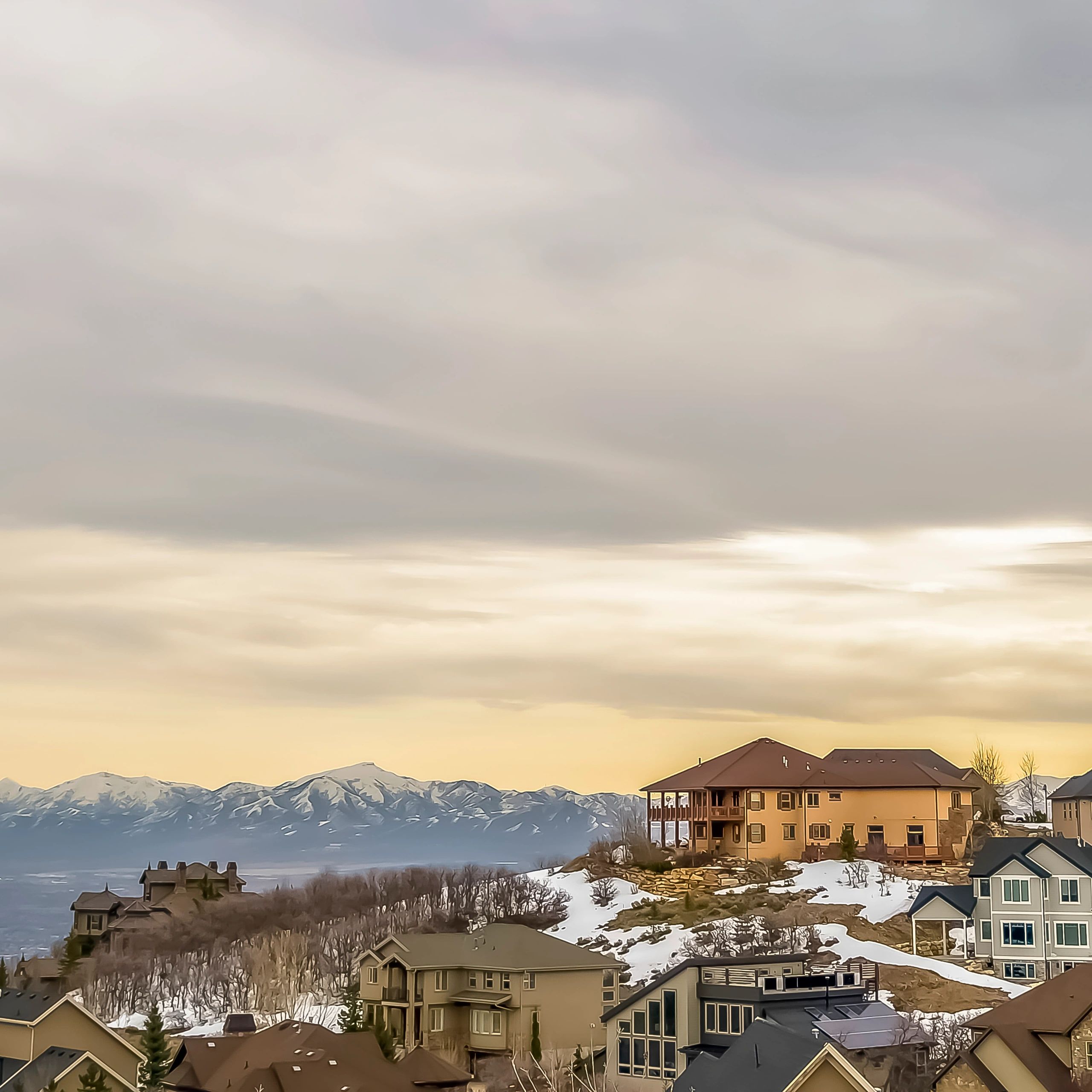 Mountain homes with snow and sunset sky.