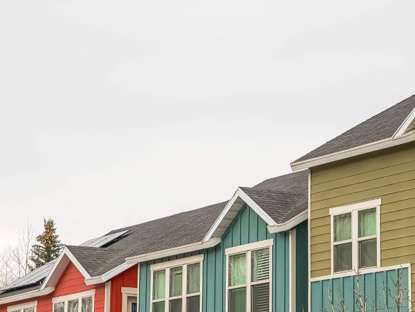 Colorful row of modern houses with distinct vibrant exteriors under a cloudy sky.