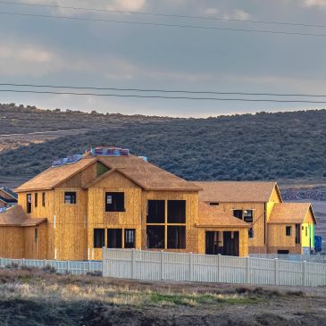 Wooden house structures under construction in a hilly area.