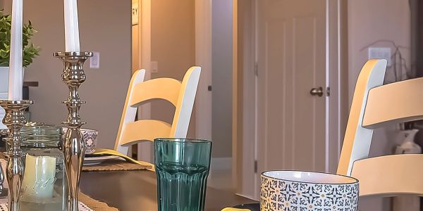 Dining table with candles, cups, and chairs.