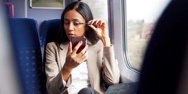 Woman applying mascara on a train.