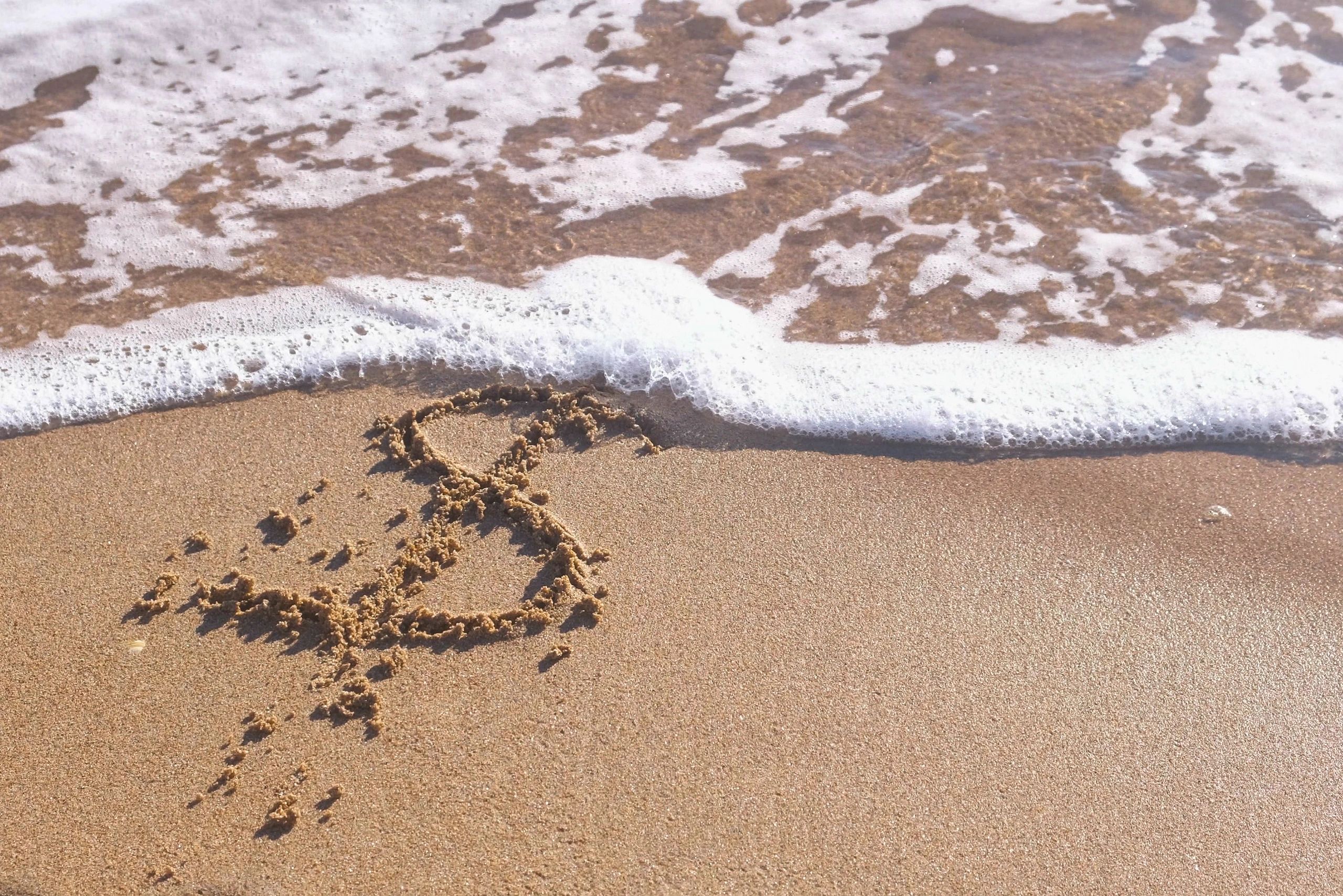 Heart drawn on the sand by the sea.