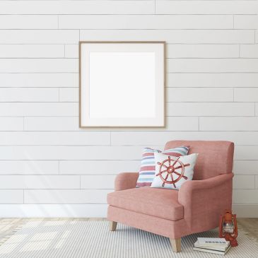 Cozy pink armchair with nautical-themed pillows in a bright, minimalist room.