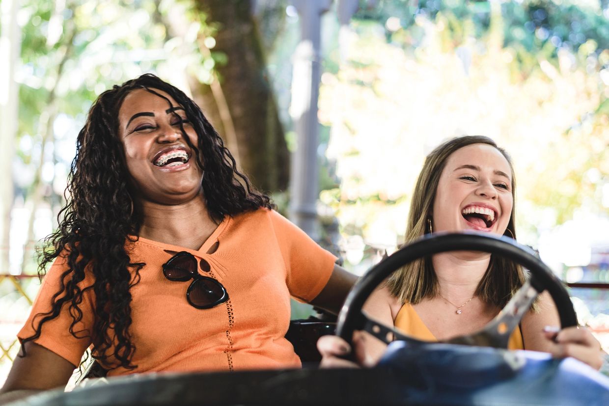 Two women laughing joyfully while riding a bumper car together.