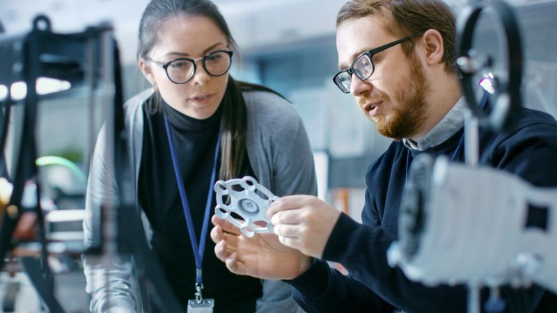 Young Talented Male and Female Engineers In a Modern Laboratory Discussing Prototype built with the Help of 3D Printer.