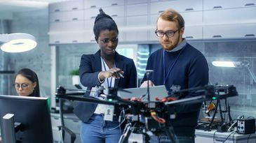 Two engineers discussing a drone prototype in a modern lab.