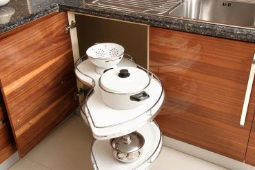 Kitchen corner cabinet with pull-out shelves holding pots and colander.