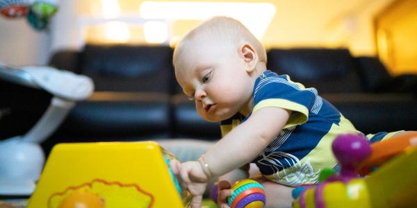 Baby intently playing with colorful toys on the floor.