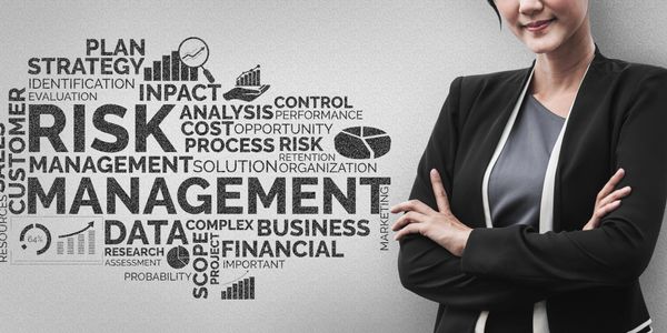 Confident professional woman stands next to risk management word cloud.