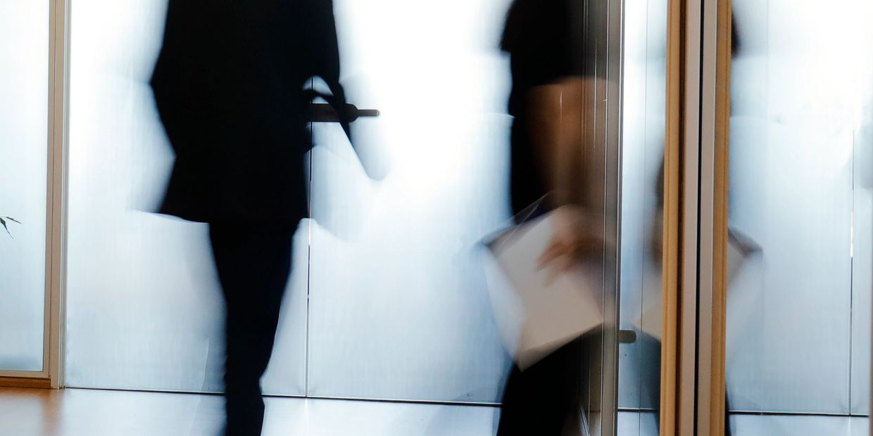 Blurry silhouettes of business people walking in an office corridor.
