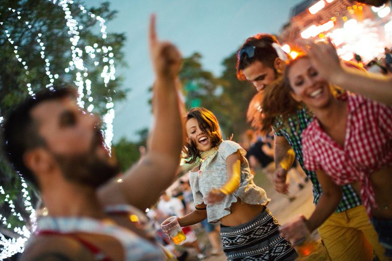 Friends dancing and jumping at music festival.