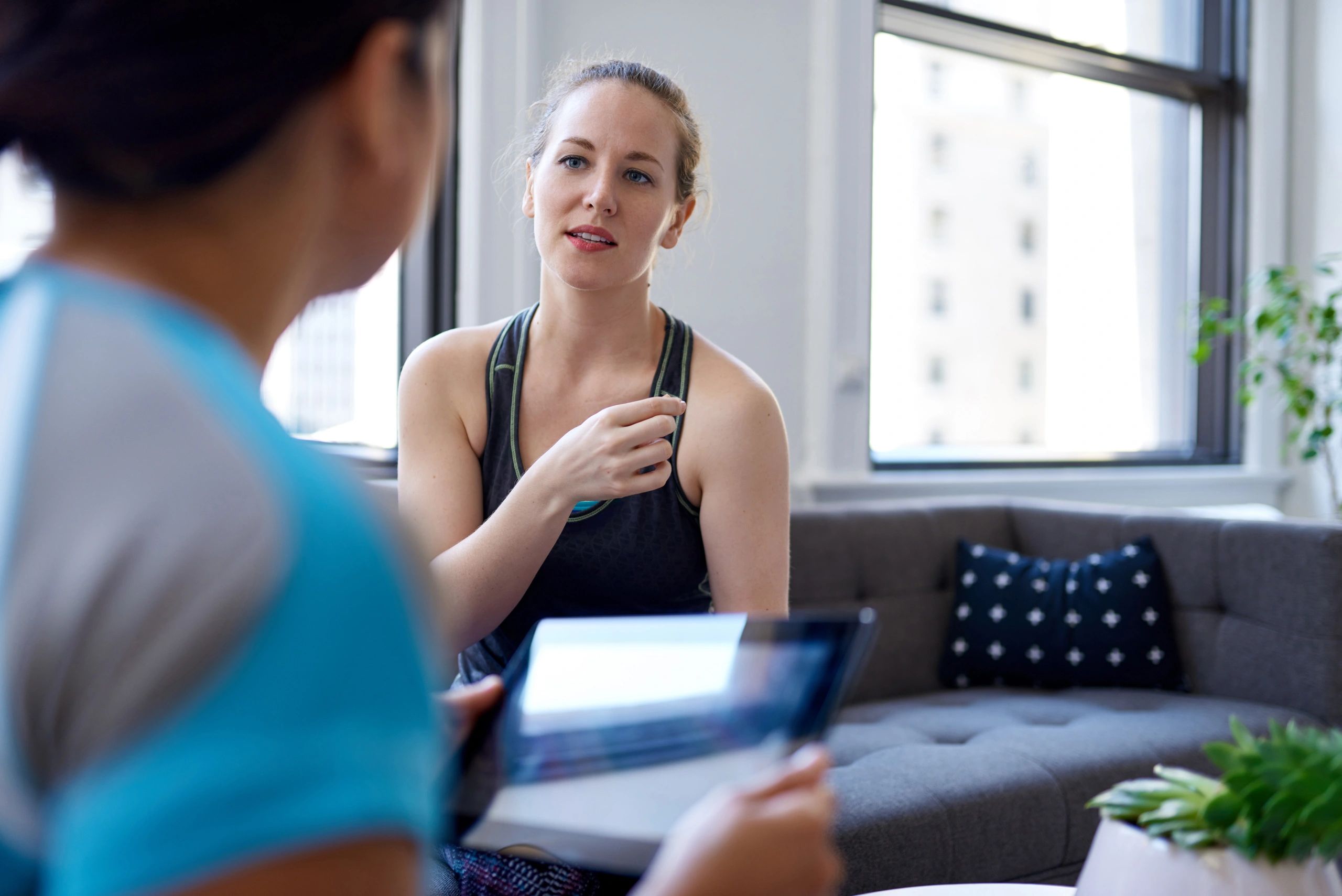 Two women having a focused conversation indoors with a tablet.