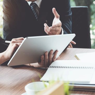 Two professionals discussing work using a tablet in a meeting.