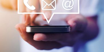 Hand holding a smartphone with contact icons.