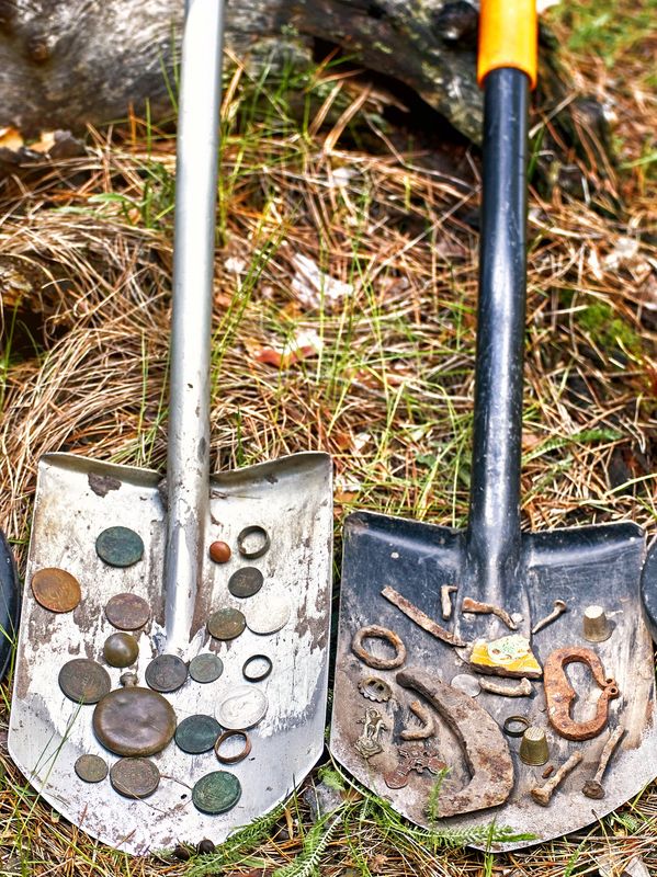 Two metal detectors and shovels with found items.