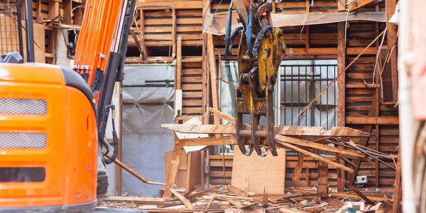 Construction machinery demolishing a wooden structure.