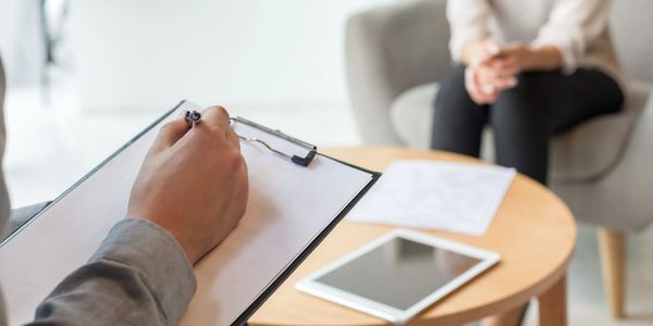 A therapist taking notes during a counseling session with a patient.