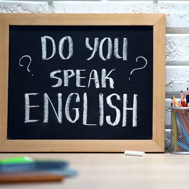 Chalkboard asking, 'Do you speak English?' with American flag.