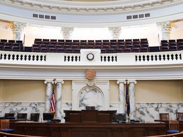 Interior of a classic courtroom with wooden benches and marble pillars.