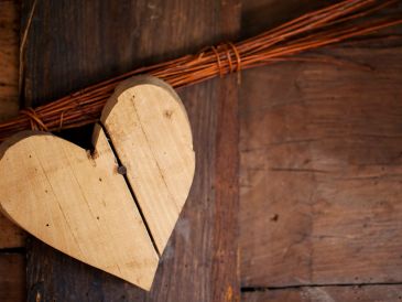Wooden heart decoration hanging on a rustic door.
