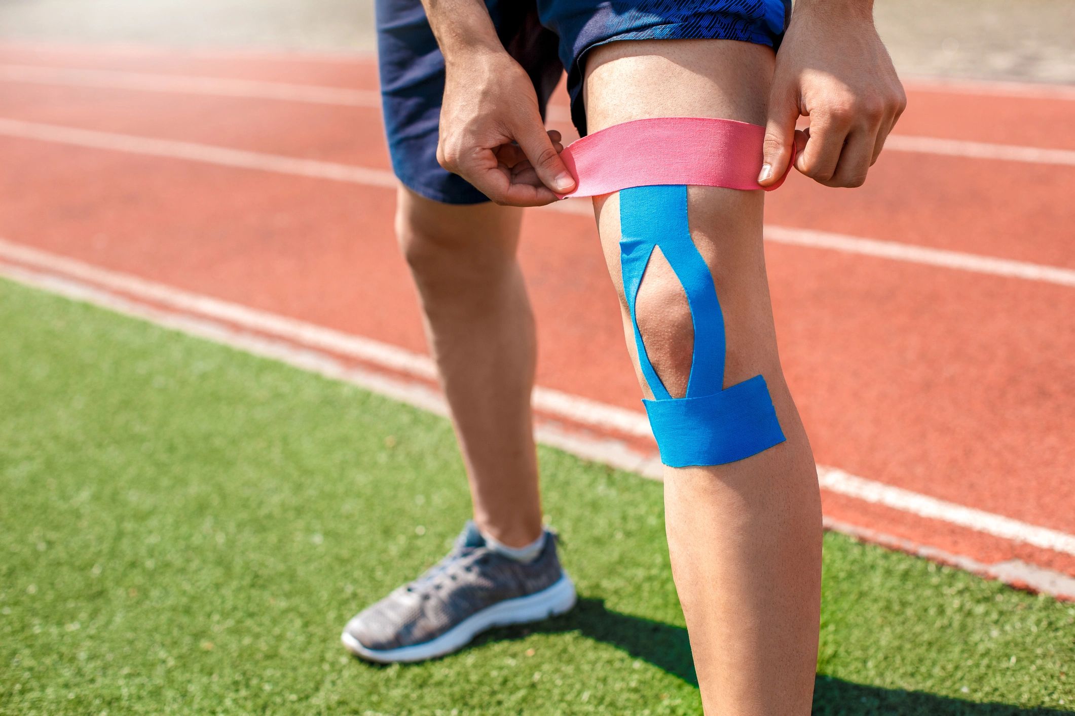 Athlete taping knee with kinesiology tape.