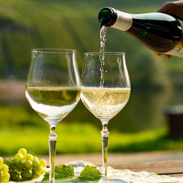 White wine being poured into glasses outdoors.