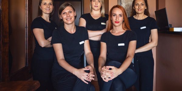 Five women in black uniforms posing indoors.