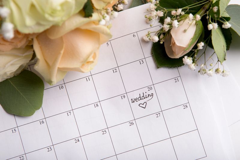 Choosing wedding date with pen writing heart on paper calendar on background