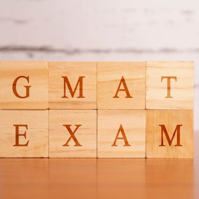 Wooden blocks spelling out GMAT EXAM on a wooden surface.