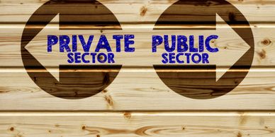 Wooden signpost with arrows pointing to private and public sectors.