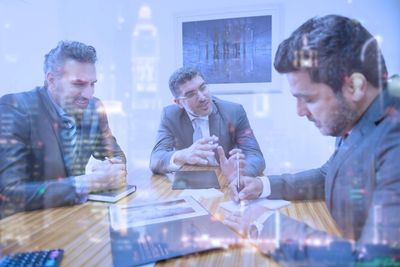 Three businessmen having a meeting with city overlay.