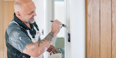 Handyman painting interior door trim during a home repair project.