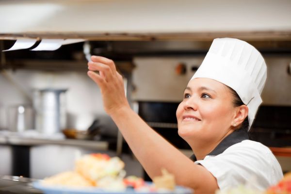 Chef reaching for order tickets in a busy kitchen.