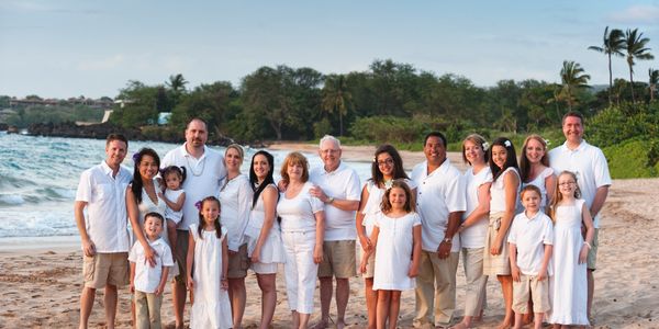 Large family posing together on a sandy beach at sunset.