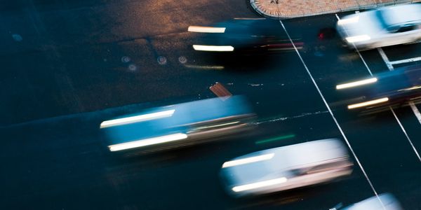 Blurred cars speeding on a dark street at night.