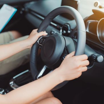 Person holding a car steering wheel while driving.