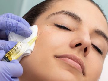 A woman receiving a cosmetic injection on her face.