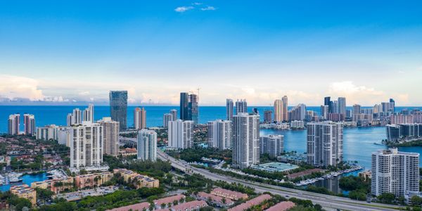 Aerial view of Aventura, Florida, with waterfront buildings and the coast in the distance.