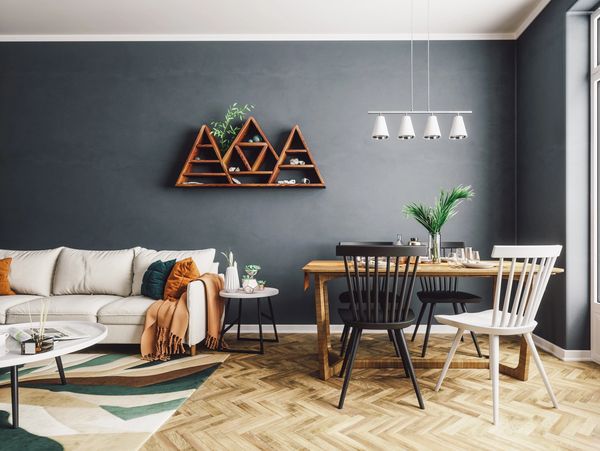 Modern living and dining area with dark walls and wooden furniture.