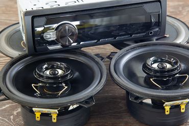 Car stereo system with two round speakers on a wooden surface.