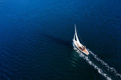 Sailboat moving through calm, deep blue water.