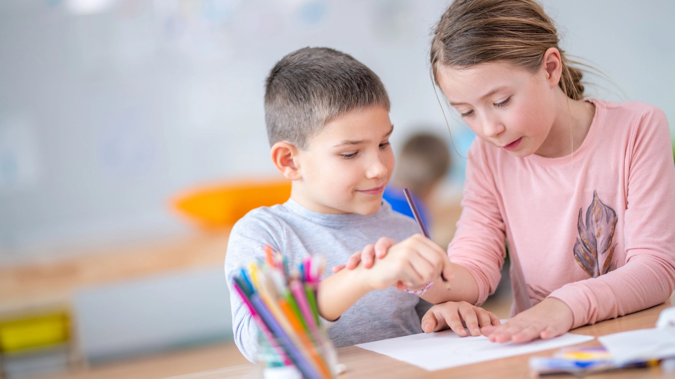 Two children drawing together at a table.