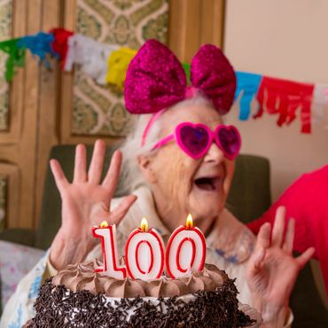 Elderly woman celebrating her 100th birthday with a joyful companion.