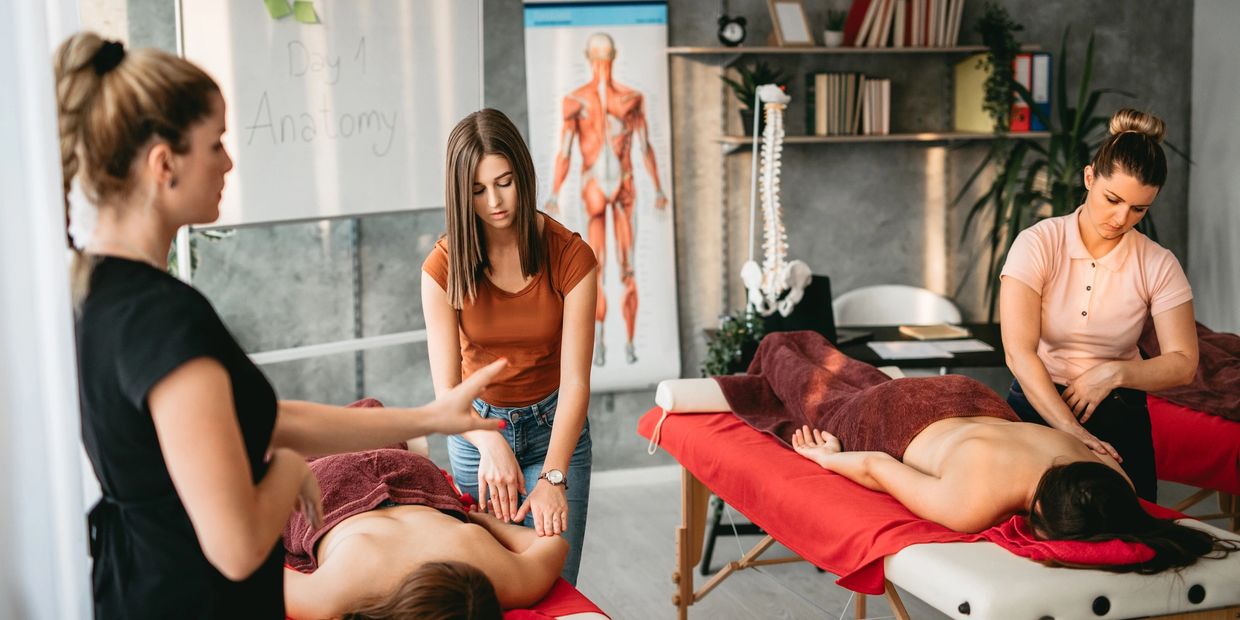 Massage therapy training with instructor and students practicing on clients.