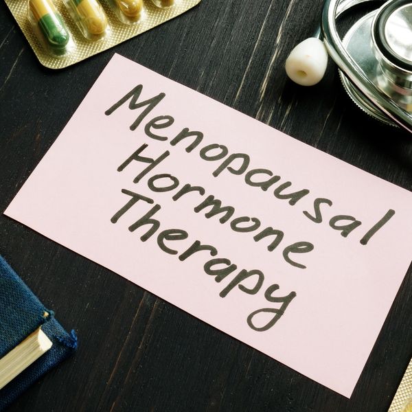 Note card reading Menopausal Hormone Therapy with pills and stethoscope.